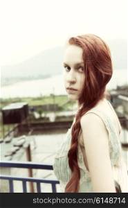 Portrait of beautiful young woman with long red hair, outdoors