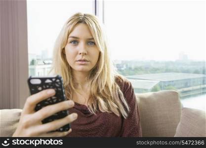 Portrait of beautiful young woman with mobile phone at home