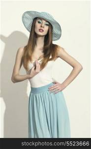 portrait of beautiful young woman with spring style, blue skirt and hat, blue make-up and long smooth brown hair