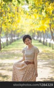 portrait of beautiful younger asian woman smiling face in summer yellow flowers blooming park happiness emotion