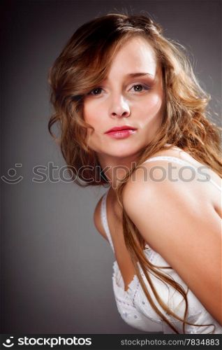 Portrait of beautiful yuong woman long curly hair on gray background