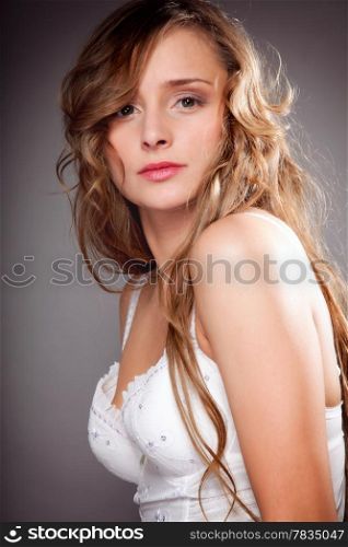 Portrait of beautiful yuong woman long curly hair on gray background