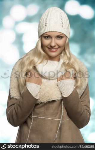 portrait of beauty blonde woman with winter style and long smooth hair. Wearing wool cap, sweater and warm coat, looking in camera and smiling