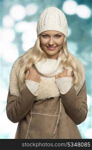portrait of beauty blonde woman with winter style and long smooth hair. Wearing wool cap, sweater and warm coat, looking in camera and smiling