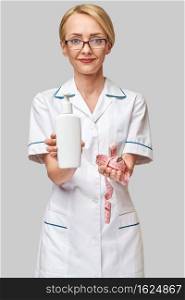 Portrait of beauty specialist standing against grey background and holding in her hand bottle of body lotion and measure tape.. Portrait of beauty specialist standing against grey background and holding in her hand bottle of body lotion and measure tape