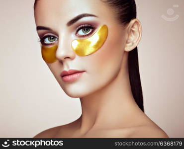 Portrait of Beauty Woman with Eye Patches. Woman Beauty Face with Mask under Eyes. Beautiful Female with natural Makeup and Gold Cosmetics Collagen Patches on Fresh Facial Skin