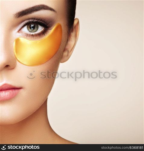 Portrait of Beauty Woman with Eye Patches. Woman Beauty Face with Mask under Eyes. Beautiful Female with natural Makeup and Gold Cosmetics Collagen Patches on Fresh Facial Skin