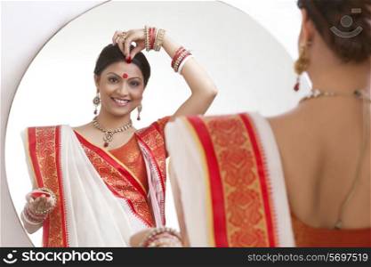 Portrait of Bengali woman putting sindoor on her forehead