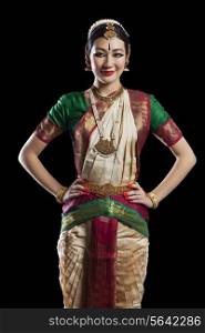 Portrait of Bharatanatyam dancer standing with hands on hips over white background