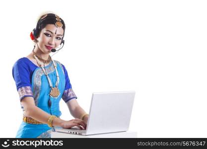 Portrait of Bharatanatyam dancer wearing headset while using laptop over white background