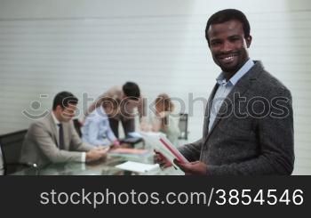 Portrait of black business man with team of people at work and talking in background during meeting in office room, male african american manager and career. 8of20