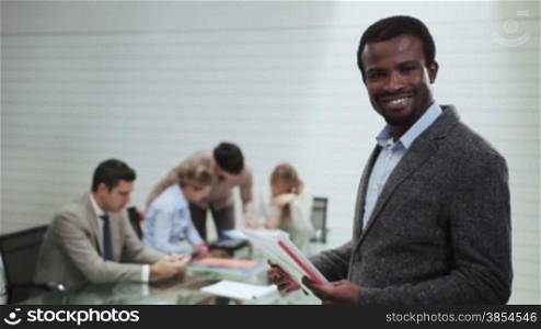 Portrait of black business man with team of people at work and talking in background during meeting in office room, male african american manager and career. 8of20