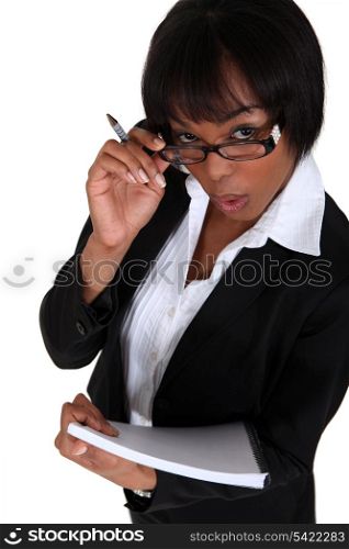 portrait of black businesswoman looking upwards holding pen and notepad
