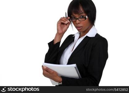 portrait of black businesswoman with glasses lowered holding notebook