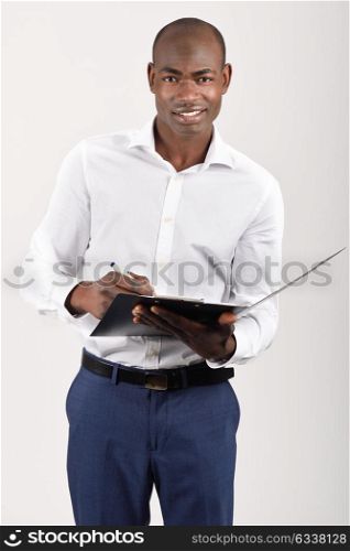 Portrait of black man wearing white shirt with a black folder in his hands in white background. Studio shot