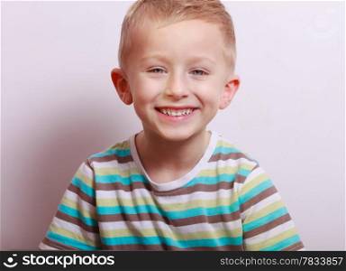 Portrait of blond cute happy laughing boy child kid at the table interior. Emotions and fun.