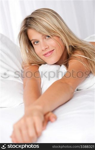 Portrait of blond woman lying in bed, looking at camera