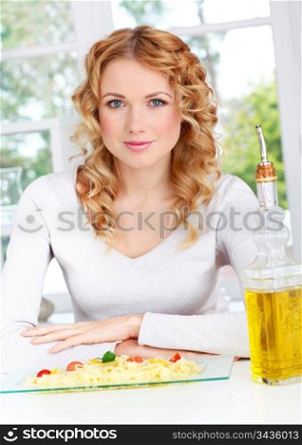 Portrait of blond woman sitting by pasta dish