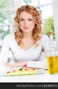 Portrait of blond woman sitting by pasta dish
