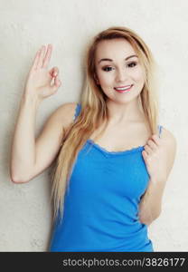 Portrait of blond woman teenage girl showing ok success hand sign gesture. Indoor.