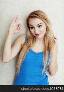 Portrait of blond woman teenage girl showing ok success hand sign gesture. Indoor.