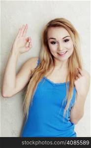 Portrait of blond woman teenage girl showing ok success hand sign gesture. Indoor.