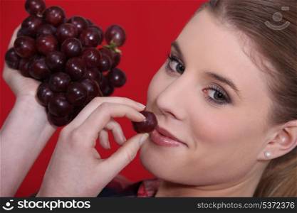 portrait of blonde eating red grapes