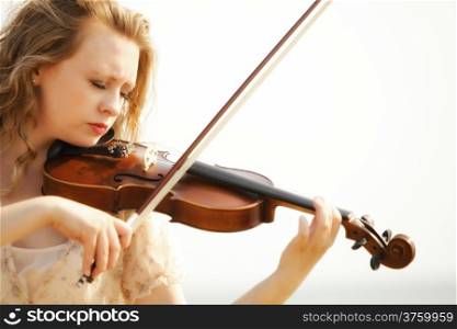 Portrait of blonde girl music lover on beach playing the violin. Love of music concept.