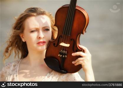 Portrait of blonde girl music lover on beach with a violin. Love of music concept.