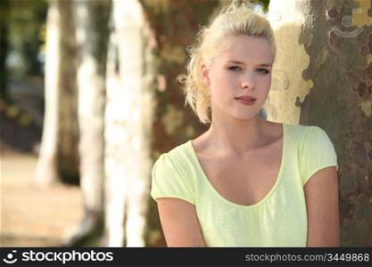 Portrait of blonde woman in front of tree trunks