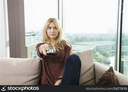 Portrait of blue eyed woman watching television on sofa at home