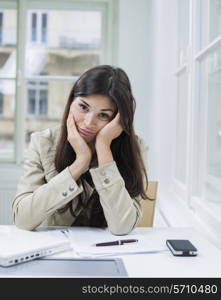 Portrait of bored businesswoman sitting at desk in office