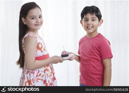 Portrait of boy and girl holding a cupcake