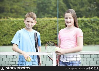 Portrait Of Boy And Girl Playing Tennis Together
