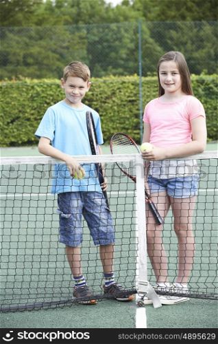 Portrait Of Boy And Girl Playing Tennis Together