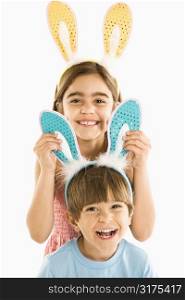 Portrait of boy and girl wearing rabbit ears smiling.