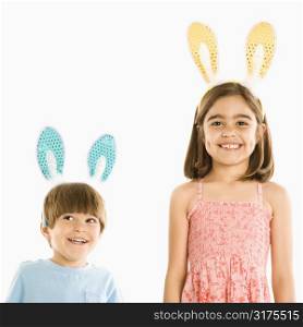 Portrait of boy and girl wearing rabbit ears smiling.