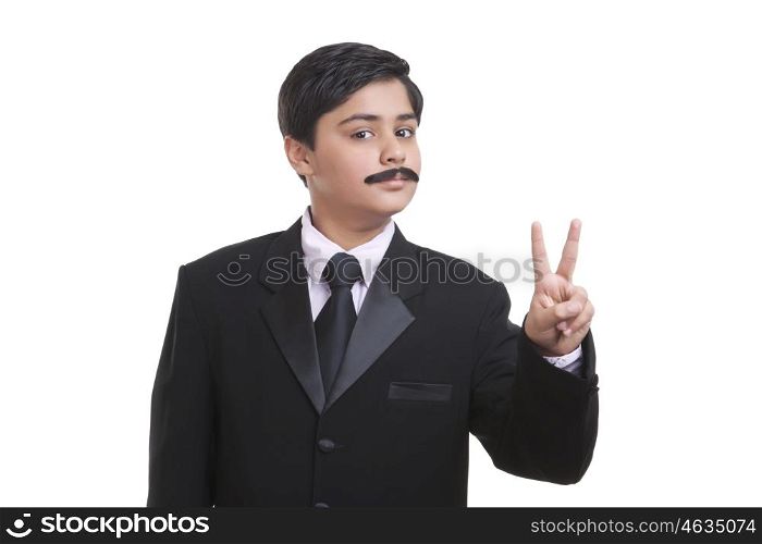 Portrait of boy dressed as businessman giving peace sign
