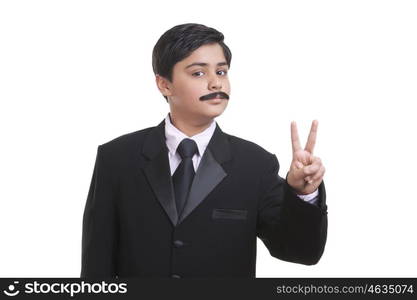 Portrait of boy dressed as businessman giving peace sign