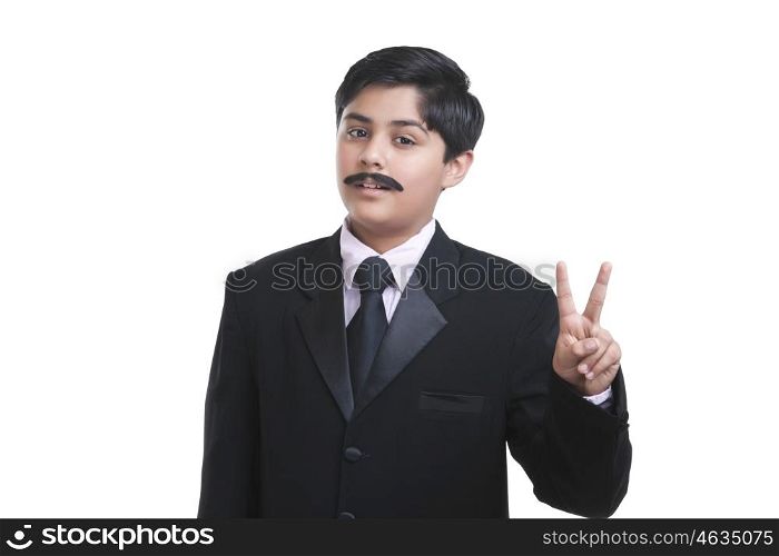 Portrait of boy dressed as businessman giving peace sign