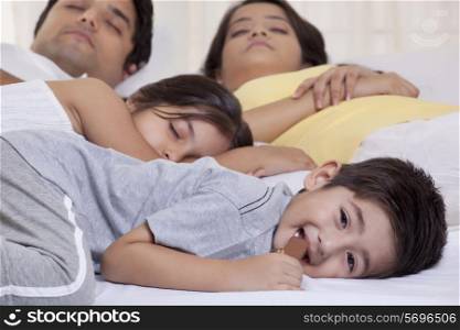 Portrait of boy eating chocolate while his family sleeping in the background