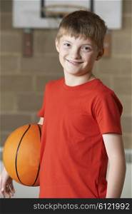 Portrait Of Boy Holding Basketball In School Gym