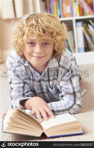 Portrait Of Boy Lying In Bedroom Reading Book