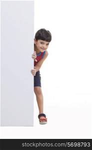 Portrait of boy peeking through billboard