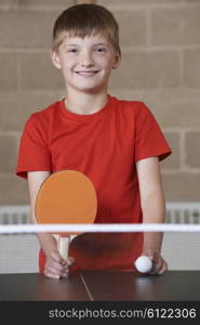 Portrait Of Boy Playing Table Tennis In School Gym