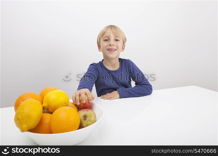 Portrait of boy with fruit bowl at table