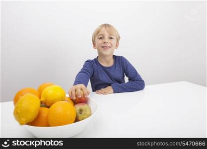 Portrait of boy with fruit bowl at table