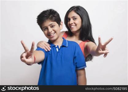 Portrait of brother and sister showing victory sign