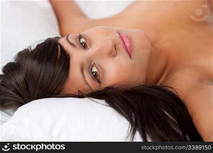 Portrait of brown hair woman in white bed, shallow DOF