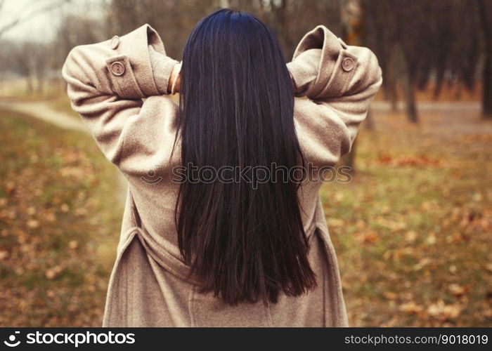 portrait of brunette hair woman in beige coat walking at the city park. portrait of brunette hair woman in beige coat walking at the city park .